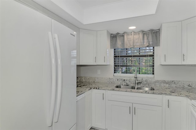 kitchen with white appliances, white cabinetry, sink, and light stone counters