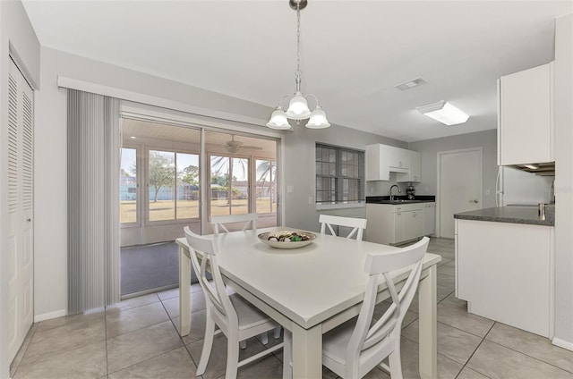 dining area with light tile patterned flooring, an inviting chandelier, and sink