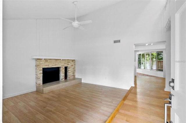 unfurnished living room with ceiling fan, a fireplace, high vaulted ceiling, and hardwood / wood-style floors