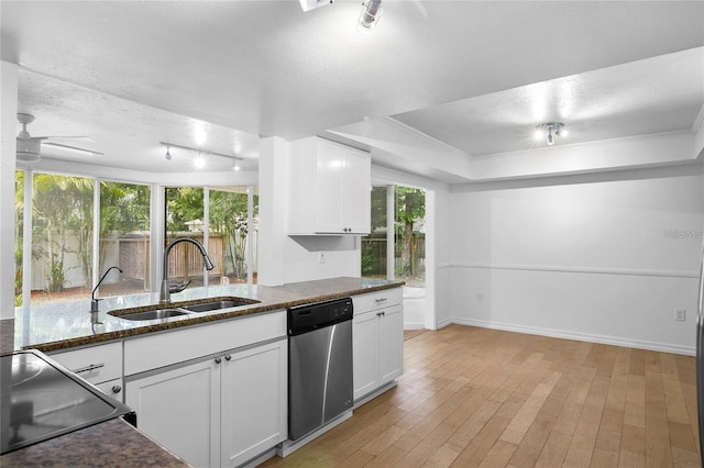 kitchen featuring a raised ceiling, sink, stainless steel dishwasher, ceiling fan, and white cabinetry