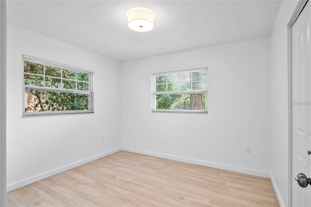 unfurnished room featuring a textured ceiling and light hardwood / wood-style flooring