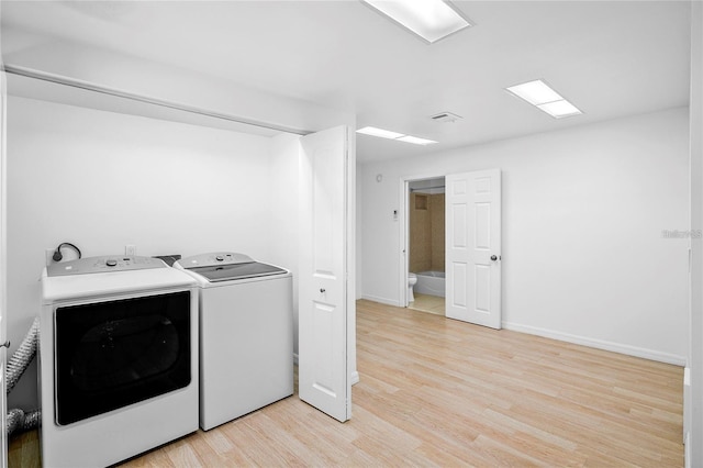 laundry area featuring washer and clothes dryer and light wood-type flooring