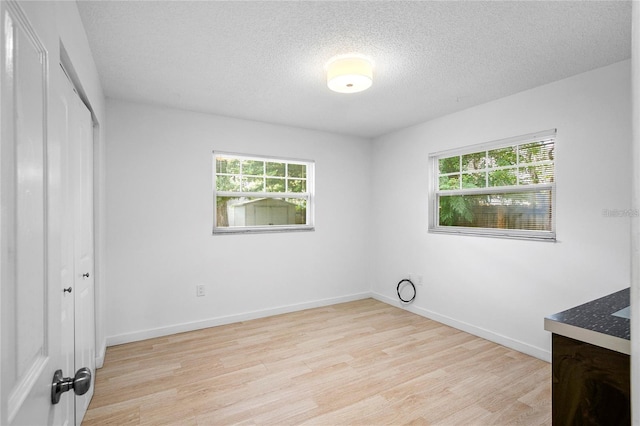 unfurnished bedroom featuring a closet, a textured ceiling, and light hardwood / wood-style flooring