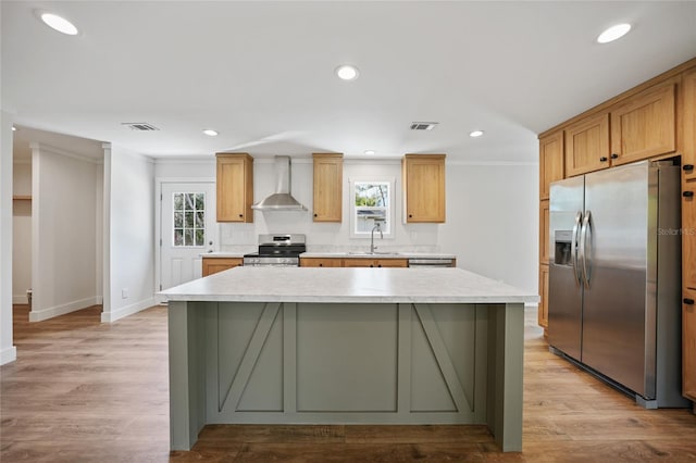 kitchen featuring appliances with stainless steel finishes, ornamental molding, sink, wall chimney range hood, and a center island