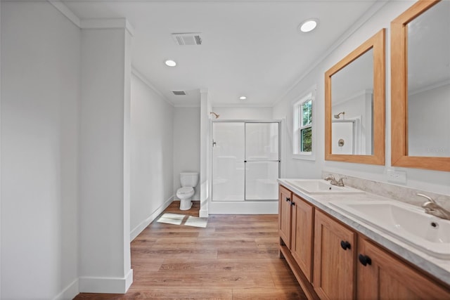 bathroom featuring wood-type flooring, an enclosed shower, toilet, vanity, and ornamental molding