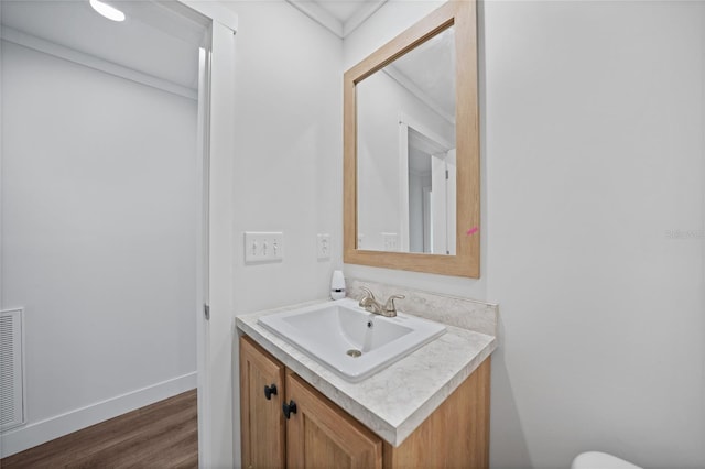 bathroom with hardwood / wood-style flooring, vanity, and ornamental molding