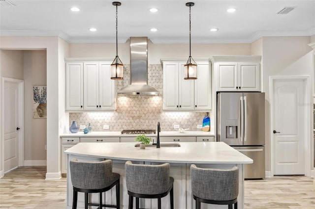 kitchen featuring appliances with stainless steel finishes, wall chimney exhaust hood, crown molding, sink, and white cabinets