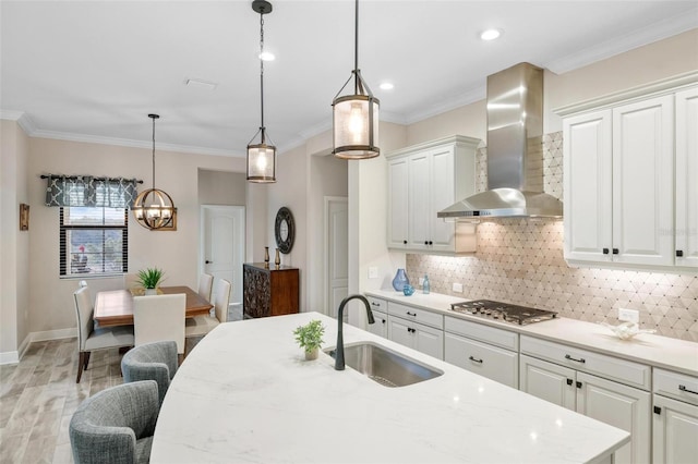 kitchen featuring sink, white cabinets, wall chimney range hood, and stainless steel gas cooktop