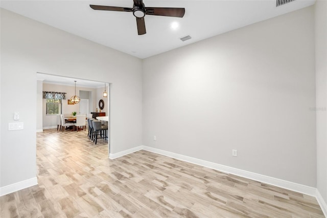 unfurnished room featuring ceiling fan with notable chandelier and light hardwood / wood-style floors