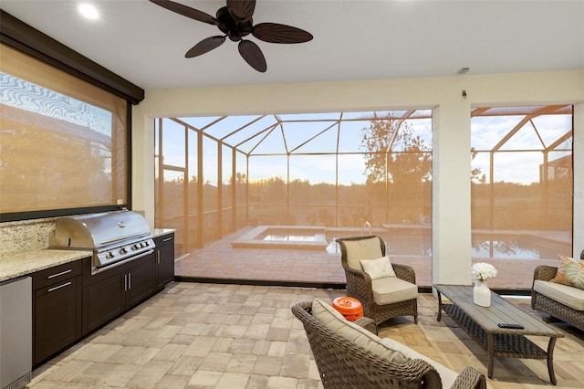 patio terrace at dusk with ceiling fan, exterior kitchen, a lanai, an outdoor living space, and area for grilling