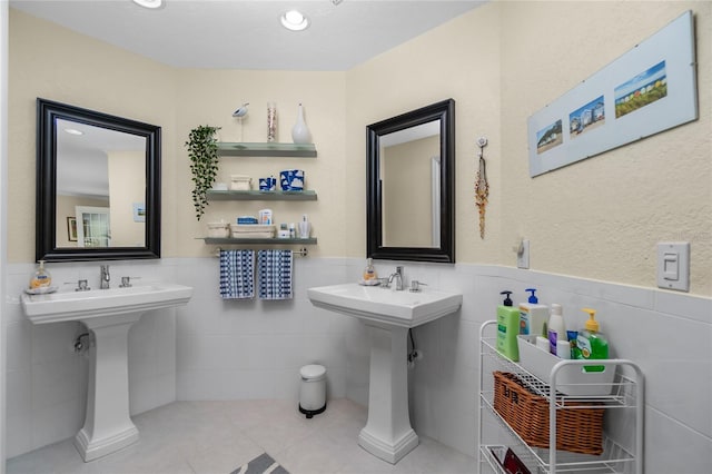 bathroom featuring tile patterned floors, dual sinks, and tile walls