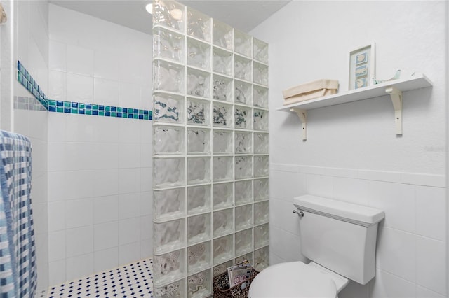 bathroom featuring toilet, tiled shower, and tile walls