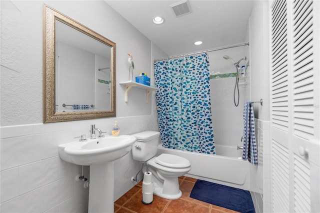 full bathroom featuring tile patterned floors, shower / bath combo with shower curtain, sink, tile walls, and toilet