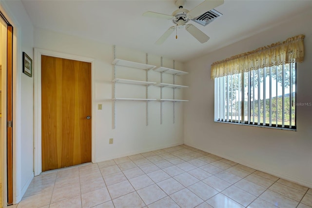 tiled empty room featuring ceiling fan