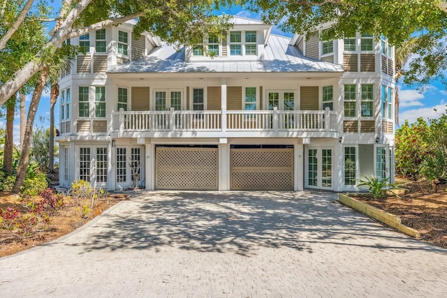 view of front facade featuring french doors, metal roof, decorative driveway, and a standing seam roof