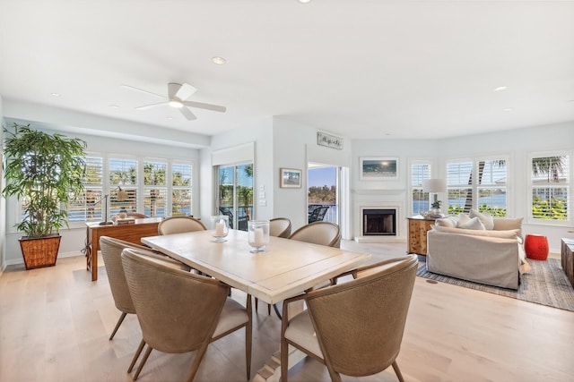 dining space featuring recessed lighting, a fireplace, light wood-type flooring, and a healthy amount of sunlight