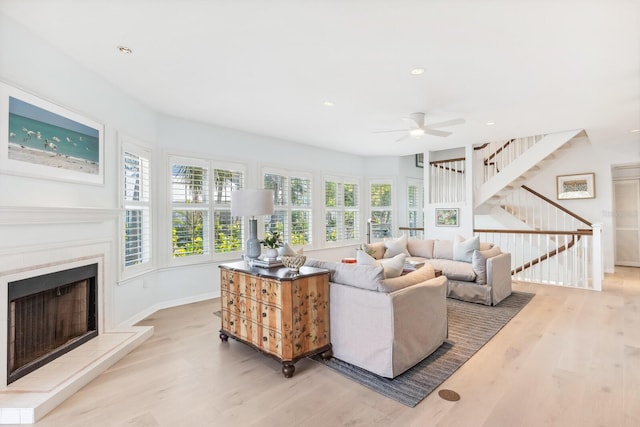 living room featuring stairway, wood finished floors, baseboards, recessed lighting, and a fireplace with raised hearth