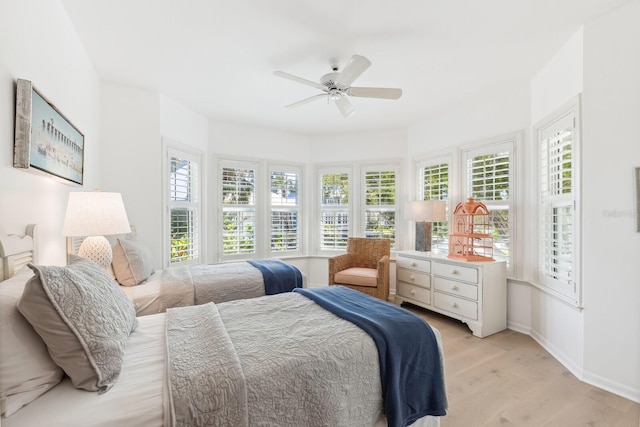 bedroom featuring light wood finished floors, a ceiling fan, and baseboards