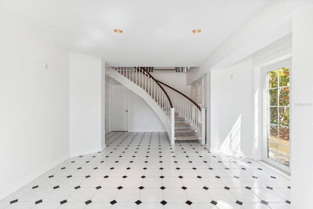 foyer with stairway, light floors, and baseboards