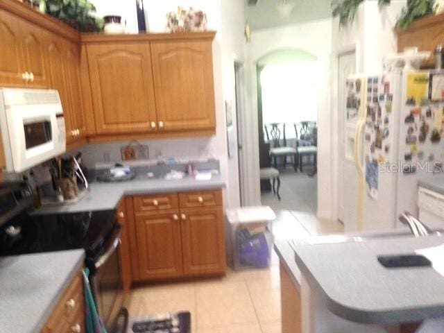 kitchen featuring light tile patterned floors and white appliances