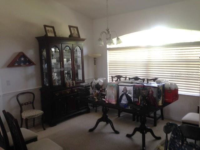 dining space with a notable chandelier, light colored carpet, and a healthy amount of sunlight