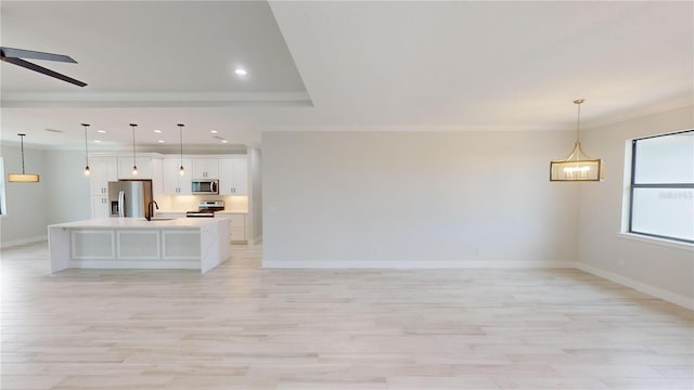 interior space with hanging light fixtures, sink, a large island with sink, and appliances with stainless steel finishes