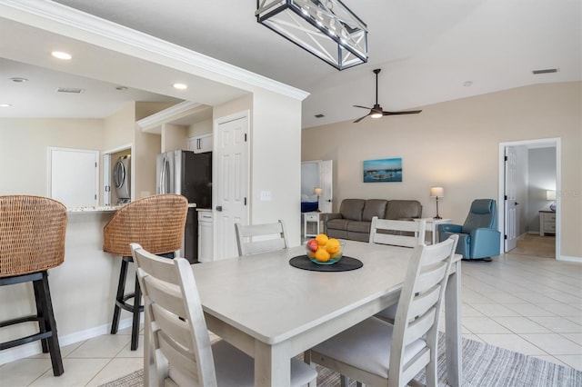 tiled dining room featuring ceiling fan, lofted ceiling, and stacked washer / dryer