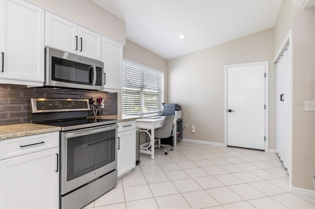 kitchen with light stone counters, backsplash, lofted ceiling, white cabinets, and appliances with stainless steel finishes