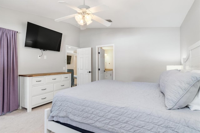 bedroom featuring ceiling fan, ensuite bathroom, light carpet, and vaulted ceiling