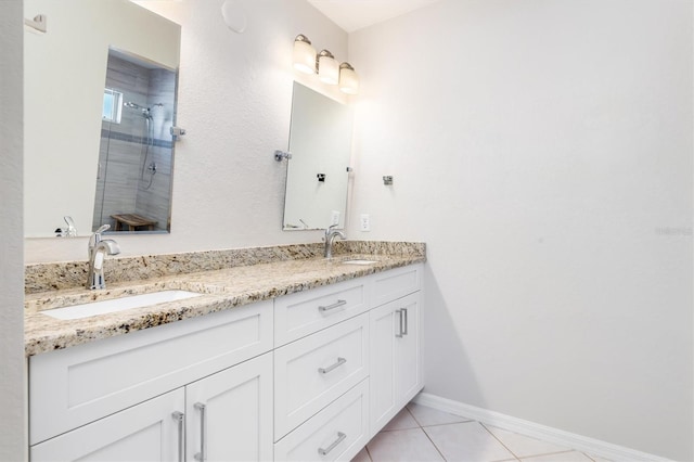 bathroom featuring tile patterned flooring, vanity, and a tile shower