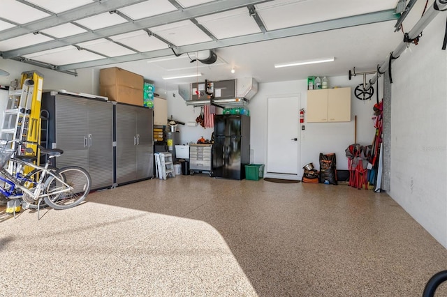 garage featuring black refrigerator, a garage door opener, and gas water heater