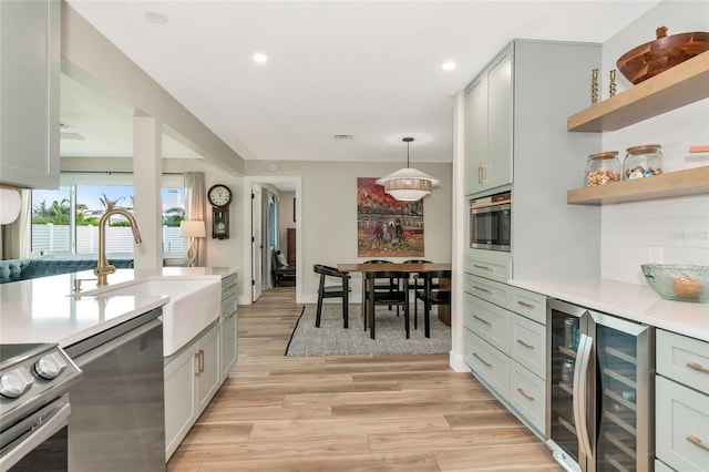 kitchen featuring beverage cooler, light hardwood / wood-style floors, pendant lighting, decorative backsplash, and appliances with stainless steel finishes