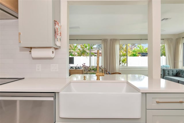 kitchen with backsplash, sink, white cabinets, and stainless steel dishwasher