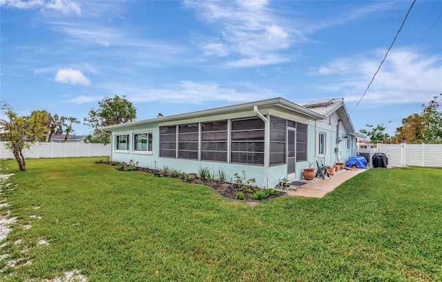 rear view of house featuring a sunroom and a yard