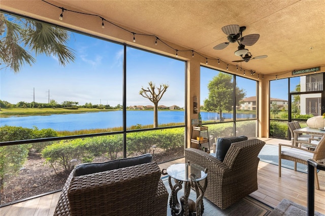 sunroom / solarium with ceiling fan, a healthy amount of sunlight, and a water view