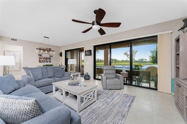 tiled living room featuring ceiling fan and a water view