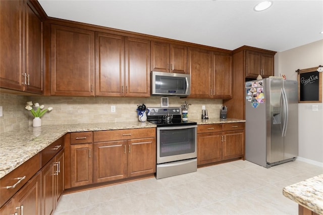 kitchen featuring tasteful backsplash, light stone countertops, light tile patterned flooring, and appliances with stainless steel finishes