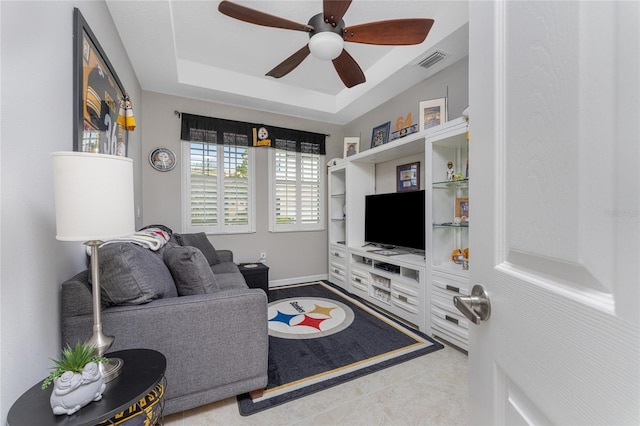 living room featuring a raised ceiling and ceiling fan