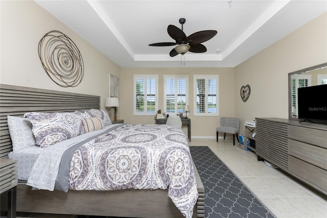 tiled bedroom with a raised ceiling and ceiling fan