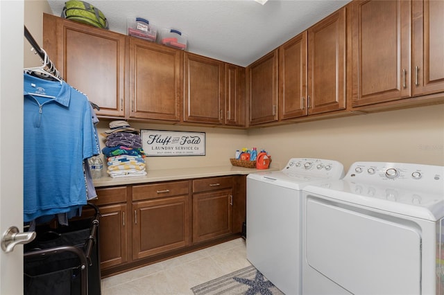 clothes washing area with washing machine and dryer, light tile patterned flooring, cabinets, and a textured ceiling