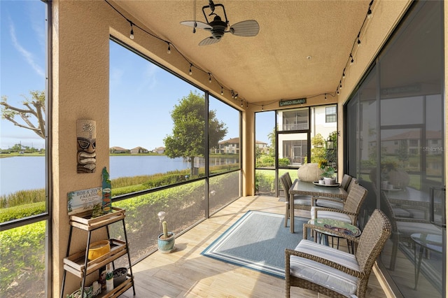 sunroom featuring ceiling fan and a water view