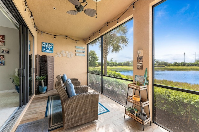 sunroom with ceiling fan and a water view