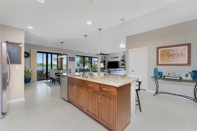 kitchen with light stone countertops, sink, ceiling fan, a center island with sink, and appliances with stainless steel finishes