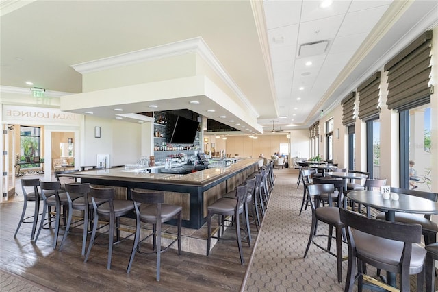 interior space featuring hardwood / wood-style floors, plenty of natural light, crown molding, and a breakfast bar area