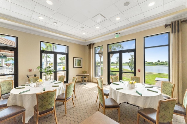 carpeted dining room featuring french doors, a water view, and a healthy amount of sunlight