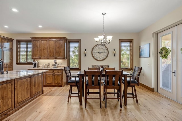 dining space with plenty of natural light, light wood-type flooring, french doors, and an inviting chandelier