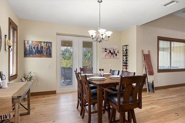 dining room with light hardwood / wood-style floors and an inviting chandelier