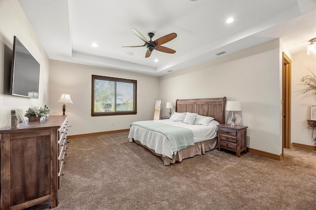 carpeted bedroom with ceiling fan and a raised ceiling