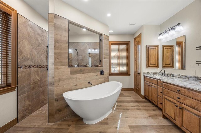 bathroom featuring plus walk in shower, hardwood / wood-style floors, and vanity