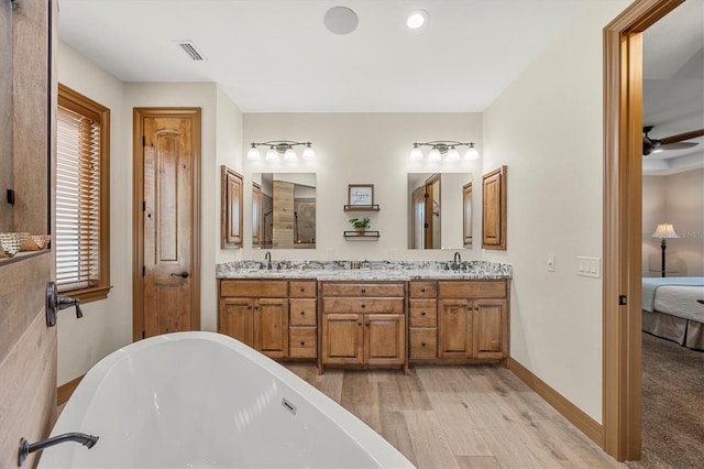 bathroom with a bathing tub, ceiling fan, vanity, and wood-type flooring